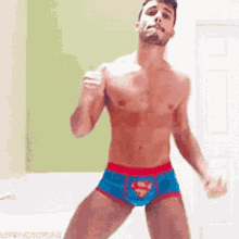 a shirtless man in superman underwear is dancing .