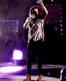 a man singing into a microphone on a stage in front of a sign that says ' rules ' on it