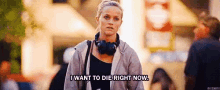 a woman wearing headphones is walking down the street and saying `` i want to die right now . ''