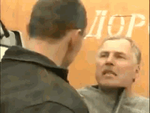 two men are having a fight in front of a sign that says aop .