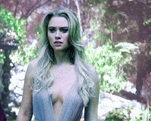 a woman in a very plunging neckline dress is standing in the woods