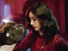 a woman in a red dress is holding a dog 's head .