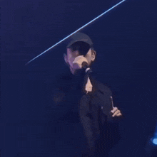a man is singing into a microphone while wearing a hat
