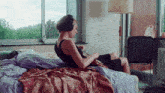 a woman wearing headphones sits on a bed with a guitar