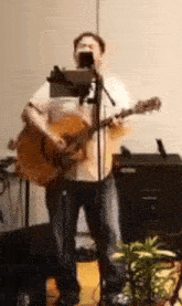a man playing an acoustic guitar and singing into a microphone