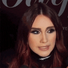 a close up of a woman 's face wearing a choker .