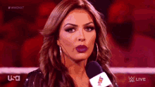 a woman is talking into a microphone while standing in a wrestling ring .