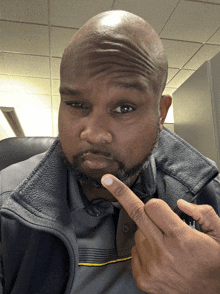 a man wearing a gray jacket is pointing at his shirt
