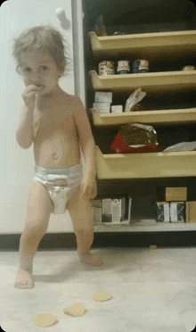 a little boy in a diaper is standing in front of a fridge