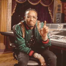 a man wearing glasses and a green jacket is sitting in front of a mixing board