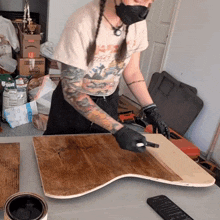 a woman wearing a mask is painting a piece of wood with a can of union paint in the background