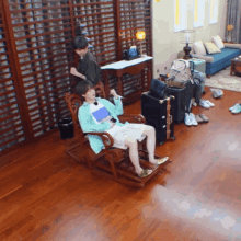 a man sits in a rocking chair with his legs crossed in a living room