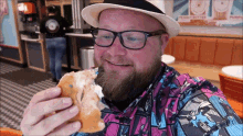 a man wearing glasses and a hat eating a donut