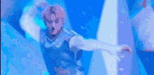 a man with pink hair is dancing on a stage in a blue light .