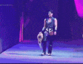 a woman in a leather outfit is holding a wrestling championship belt on a stage