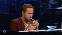 a man in a red suit is smoking a cigarette while sitting at a piano .