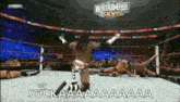 a wrestler is standing in the middle of a wrestling ring with his arms in the air and says suckaaa