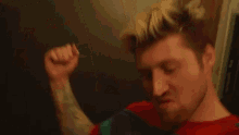 a man with a lot of tattoos on his arm is pointing at himself in the mirror .