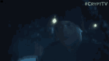 a man in a black hat is standing in the dark .