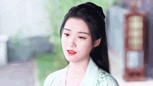 a woman with a ponytail is wearing a green jacket