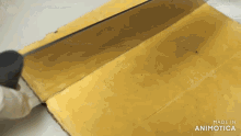 a knife is being used to cut a piece of cheese and the words made in animotica can be seen in the corner