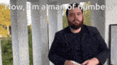 a man with a beard says " now i 'm a man of numbers " while holding a phone