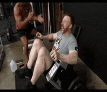 a man in a gray shirt is sitting on a machine with his legs crossed