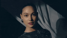 a close up of a woman 's face with a shadow on the wall behind her