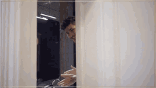 a man peeking out from behind a shower curtain
