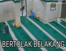 a man is praying in a mosque while another man sits in a chair .