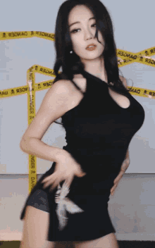 a woman in a black dress is dancing in front of tape that says " danger "