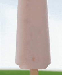 a woman is standing in front of a giant pink ice cream bar .