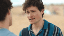 a young man with curly hair is talking to another young man