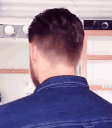 the back of a man 's head with a shaved head and a beard .