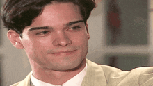 a man wearing a suit and tie is smiling