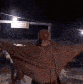 a person with their arms outstretched is standing in front of a street sign that says ' downtown ' on it .
