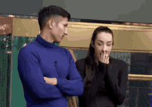 a man in a blue turtleneck is standing next to a woman