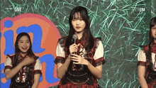 a girl is holding a microphone while standing in front of a crowd .
