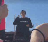 a person is taking a picture of a person wearing a black shirt that says thunderbus