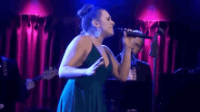 a woman in a green dress is singing into a microphone .