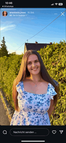 a woman in a floral dress is standing in front of a hedge