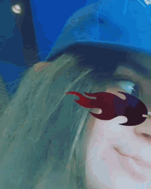 a woman wearing a blue hat and red flames sunglasses smiles