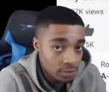 a man in a hoodie is sitting in a chair looking at the camera .