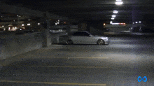 a car is parked in a parking garage with a blue infinity symbol in the corner