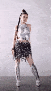 a woman is wearing a silver top and a black skirt