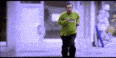 a man in a green sweater is running in a hallway .