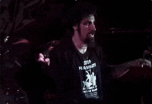a man singing into a microphone in a dark room with a shirt that says ' nirvana ' on it