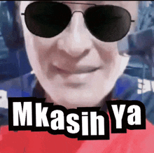 a man wearing sunglasses and a red shirt with the words mkasih ya