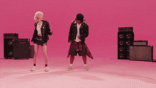 a man and a woman are dancing in front of a pink wall