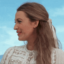 a woman wearing a white lace top with a white ribbon in her hair